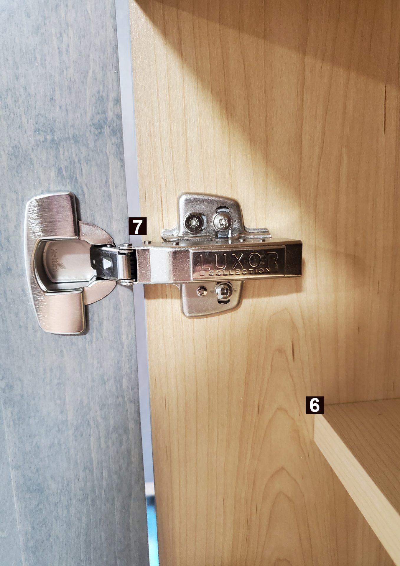 Charnière à fermeture douce sur une porte en bois, pièces numérotées 6 et 7.