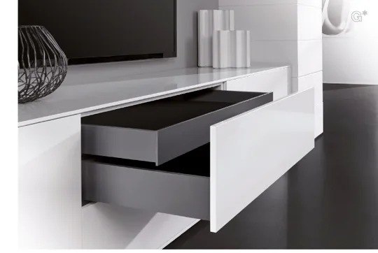 Tiroir à parois de métal graphite ouvert dans un meuble blanc lustré.