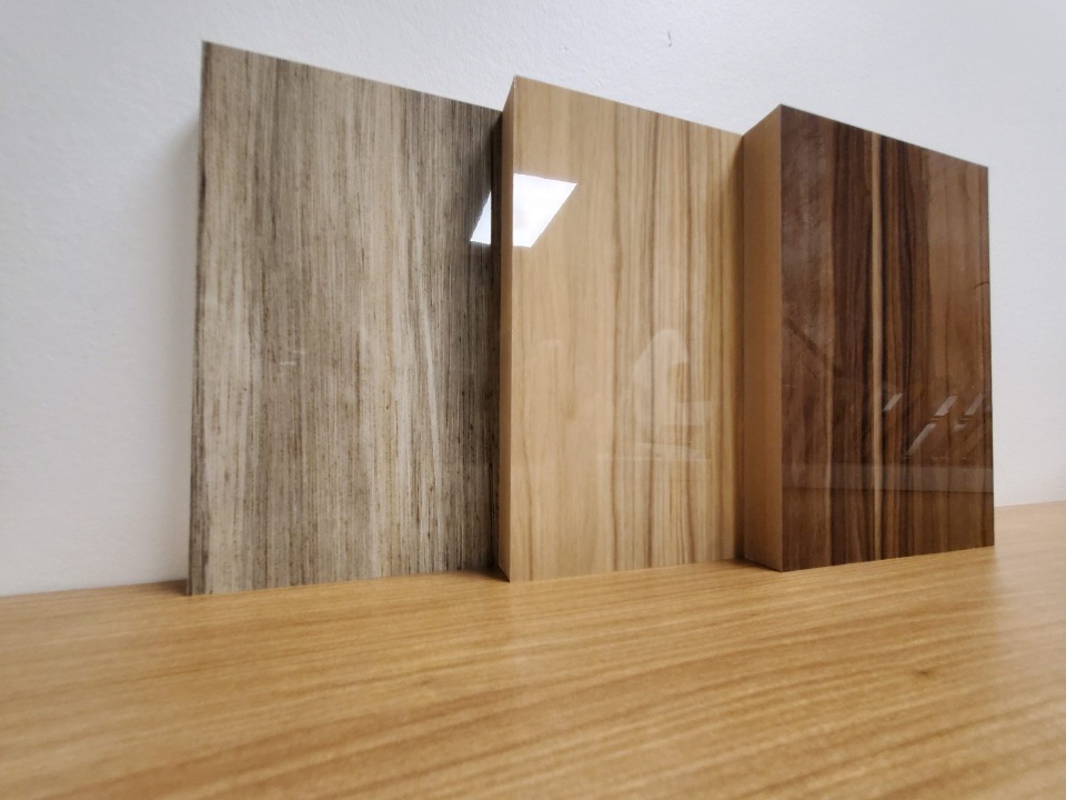 Trois panneaux de laminé veiné bois, du clair au foncé, au fini très lustré.