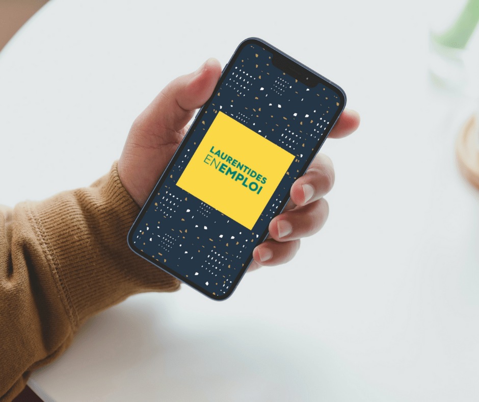 Une main tient un téléphone affichant « Laurentides en emploi ».