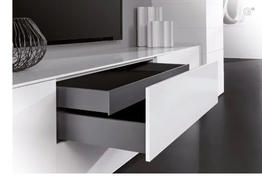 Tiroir à parois de métal graphite ouvert dans un meuble blanc lustré.