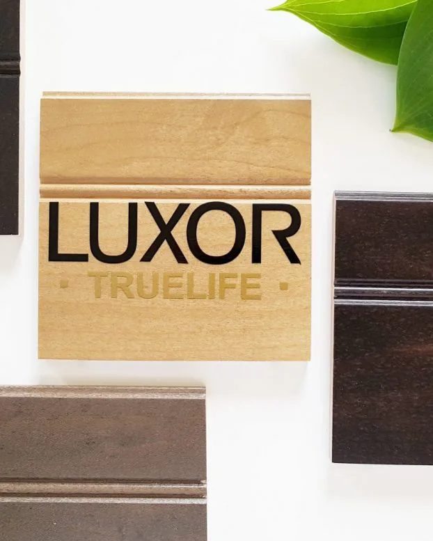 Un échantillon de bois gravé LUXOR TRUELIFE, entouré d'échantillons de finis brun, chocolat et gris